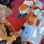 Eine ältere Frau nimmt RoboterLIO unter die Lupe. 