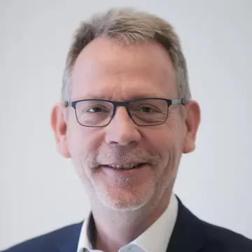 Christoph Duerdoth trägt eine Brille und ein weißes Hemd. Er lächelt. 