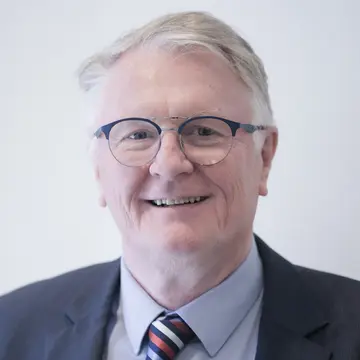 Frank Stefan lächelt, er trägt Anzug und Krawatte. 