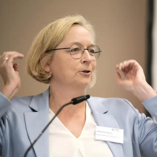 Frau Hannemann steht vor einem Mikrofon und gestikuliert mit den Armen.