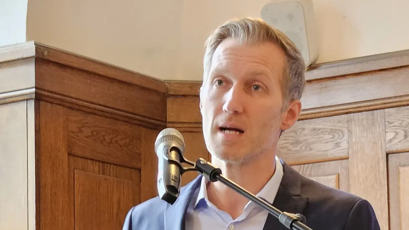 Daniel Terzenbach steht am Rednerpult, gestikuliert und spricht zu einem Publikum.