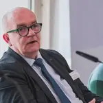 Detlef Zander sitzt vor dem Mikrofon und trägt eine schwarzen Anzug.