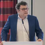 Herr Prof. Timo Meynhardt steht am Rednerpult in weißem Hemd und Jackett, bereit zu sprechen.