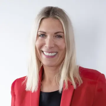 Constance von Struensee trägt einen roten Blazer, blondes schulterlanges Haar und lacht. 
