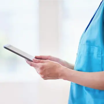 Eine Pflegerin hält ein Tablet