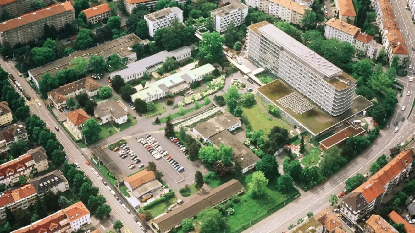 Das Bild zeigt eine Vogelperspektive auf das Felixplatterspital. Zu sehen ist ein weitläufiges Gelände mit langen Gebäuden, umgeben von Grün.